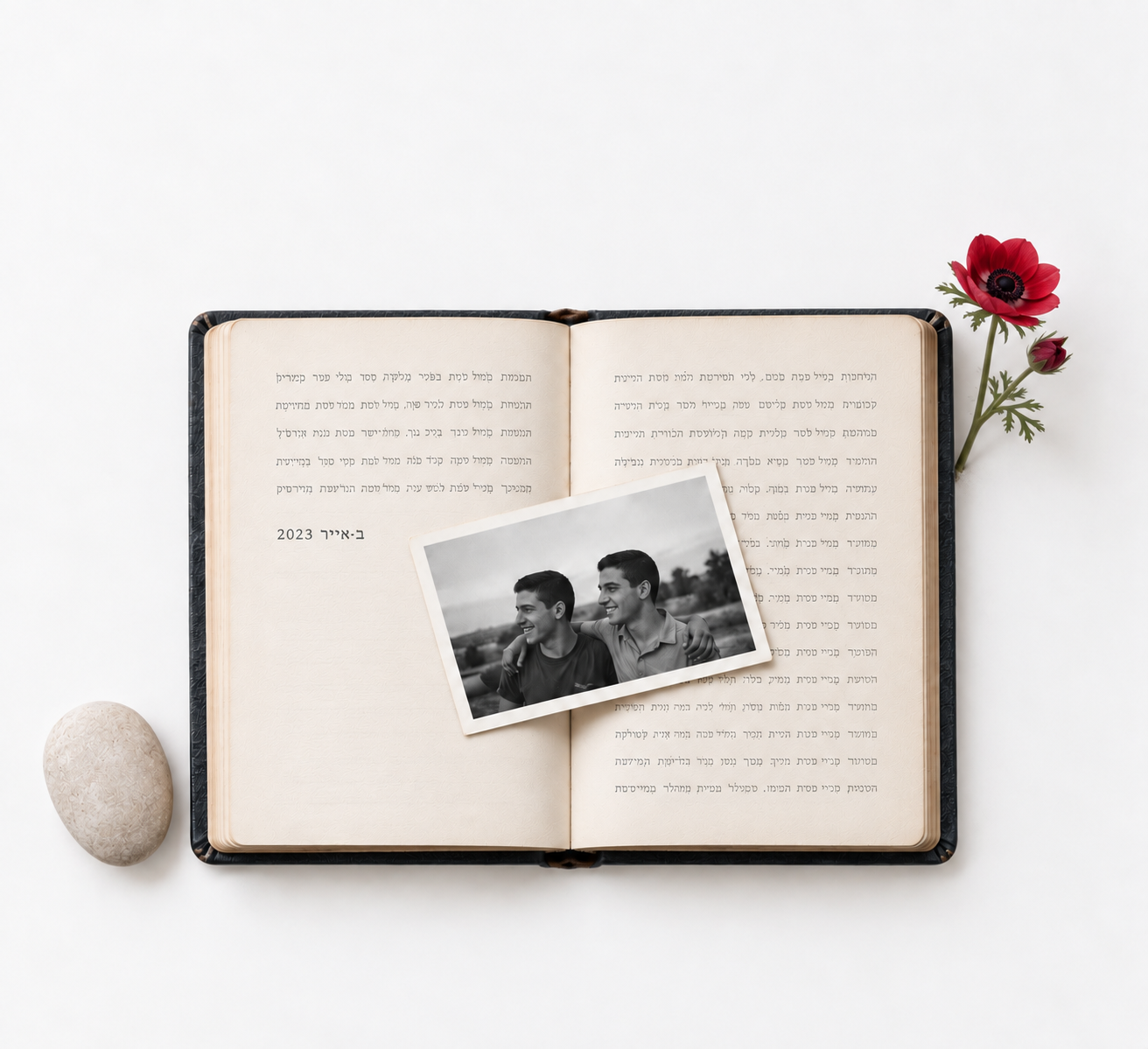 Open memorial notebook with a photograph, white stone and red anemone